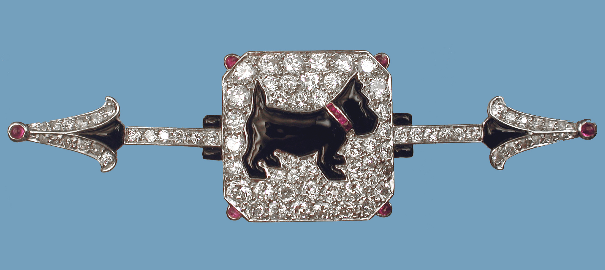 Click to see full size: Art Deco brooch worked with platinum set diamonds with cabochon cut and half cabochon rubies and enamel detail. The standing Scottish Terrier is worked in enamel and wears  a gold set calibre cut ruby collar.