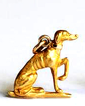 Click to see full size: A sand cast gold seated Greyhound with one leg raised.