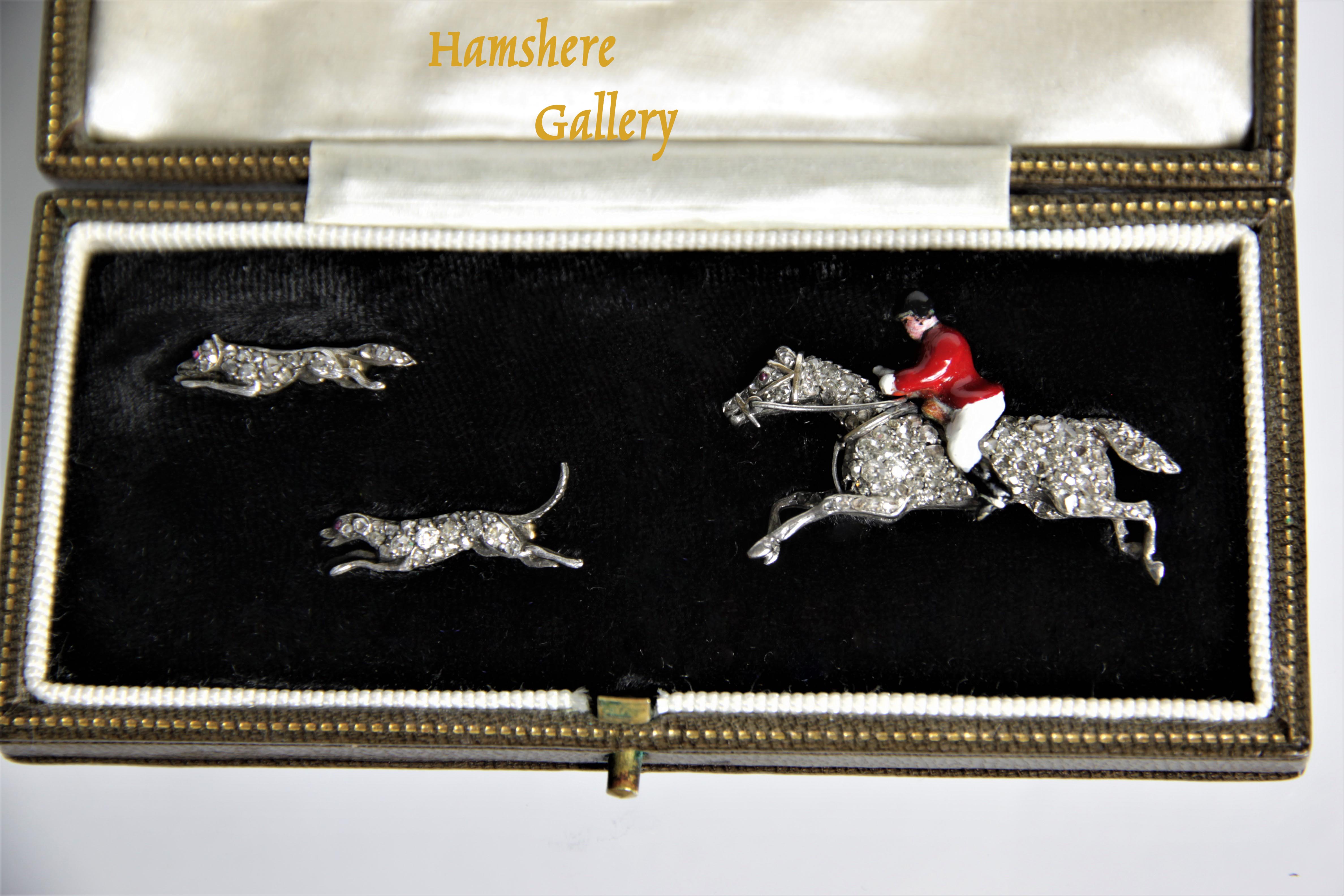 Click to see full size: An early 20th century, Garrard & Co. boxed set of diamond and enamel brooches of huntsman, hound and fox